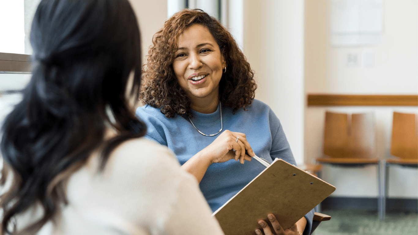 NDIS plan manager talking with a participant, holding a clipboard.