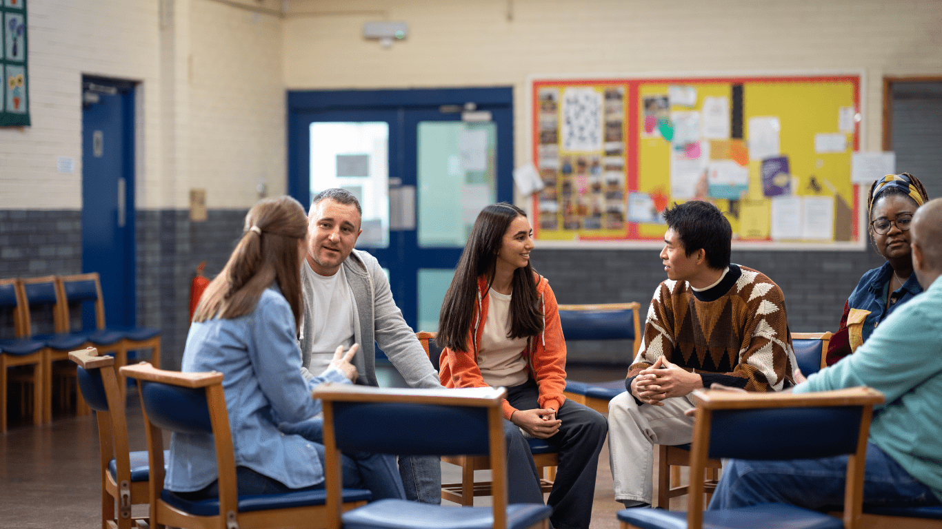 A diverse group of individuals engaging in an NDIS-supported group discussion in a community setting.