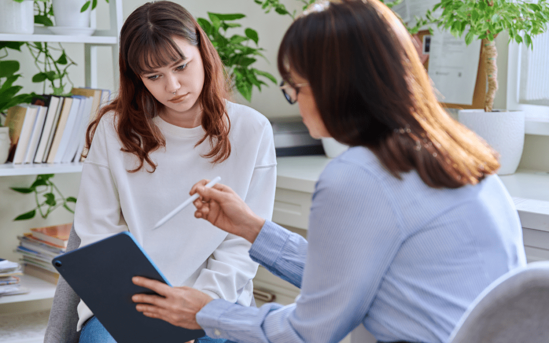 An NDIS support worker showing a participant information on a tablet during a consultation.