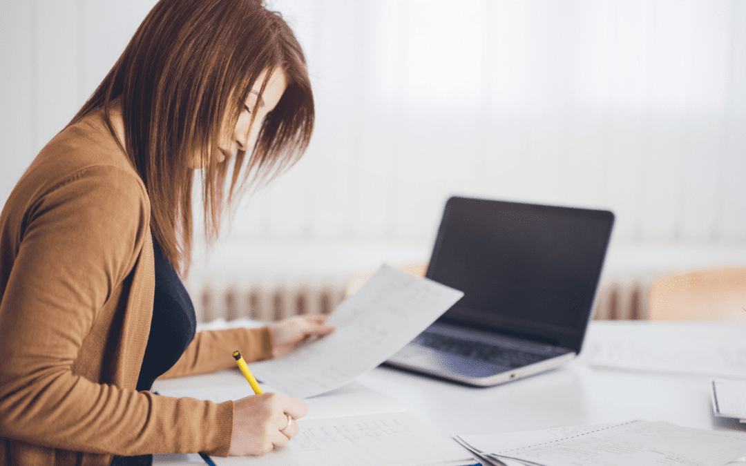 A participant reviewing and organising NDIS paperwork at a desk with a laptop.