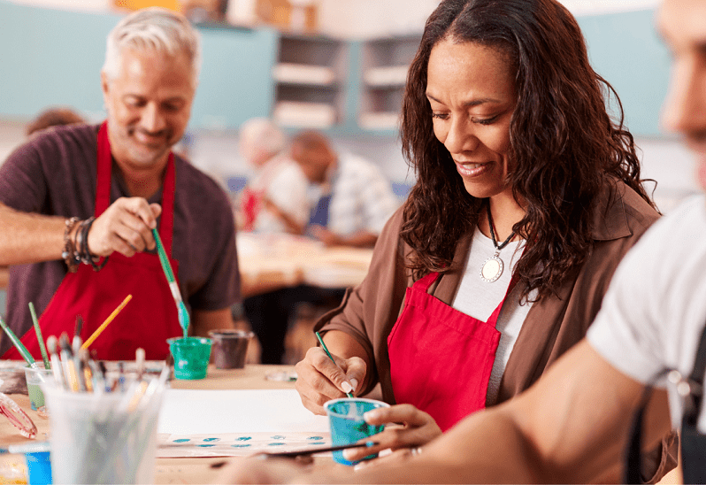 Access to a wide range of ndis providers People enjoying a group art class, smiling and painting together at a community centre.