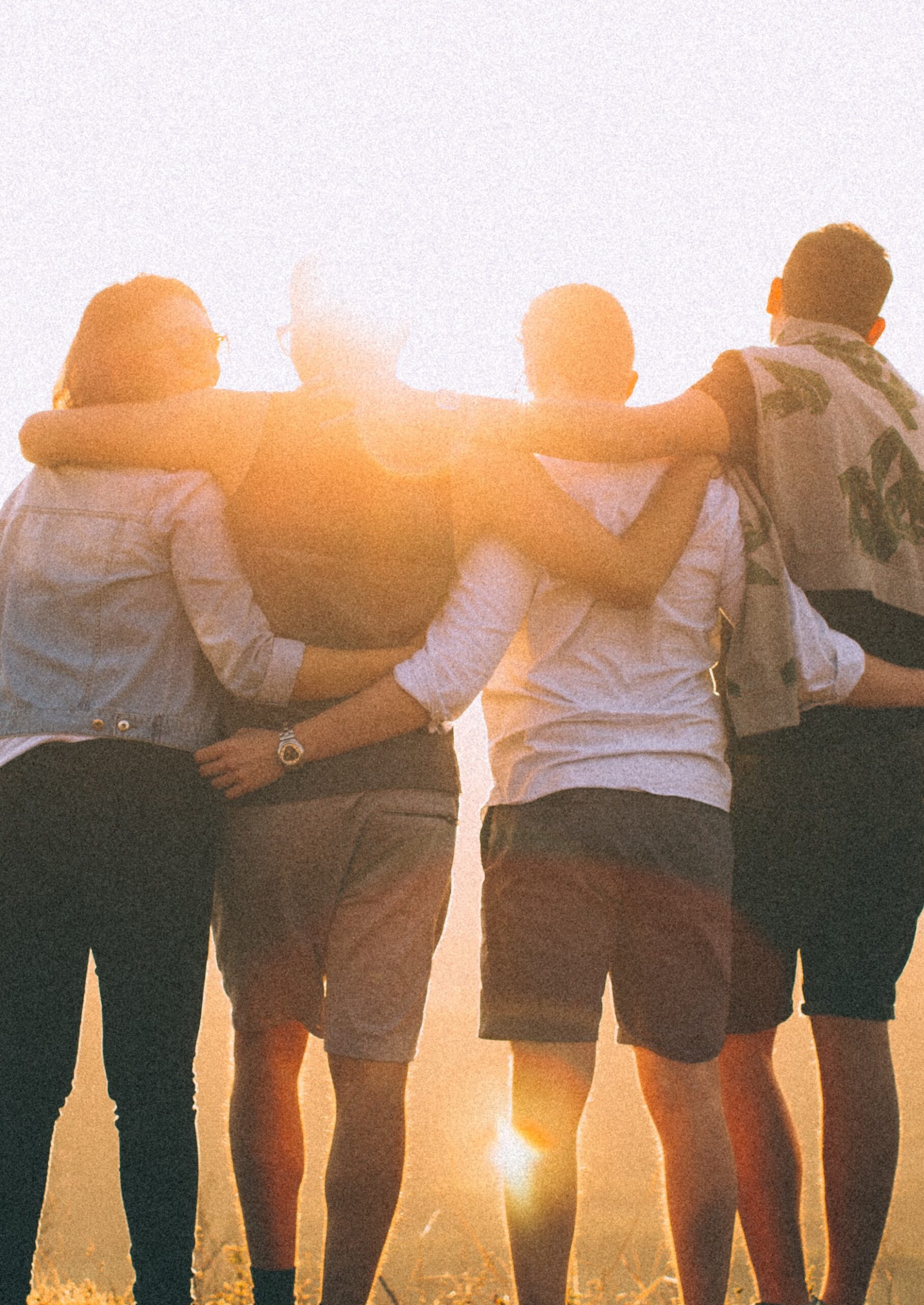 Strength in Support – Group Mental Health Recovery Four people standing with arms around each other, facing the sunset, symbolising connection, peer support, and shared recovery journeys.